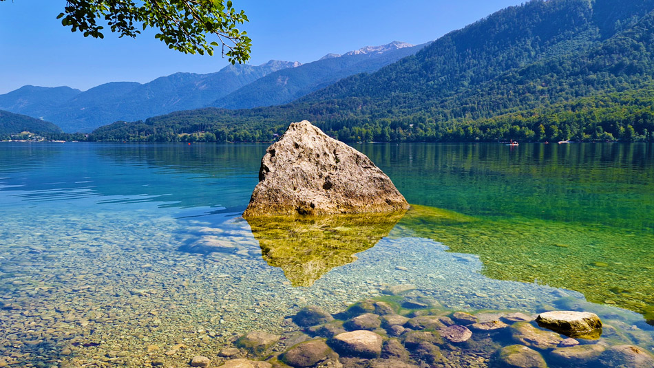 Bohinjsko jezero se ponaša s kristalno čisto vodo iz katere moli trikotna skala.