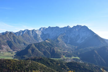 Virnikov Grintovec se ponaša z razgledom na zgornjo jezersko dolino in gore, ki se dvigajo visoko nad njo.